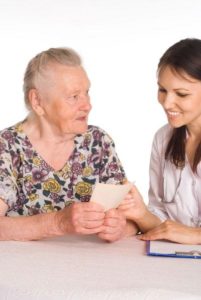 Bilde av en eldre dame som prater med helsepersonell