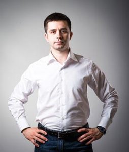 Bilde av en mann i hvit skjorte som holder hendene på hoftene og ser fast mot kamera